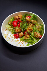 White bowl with lettuce, tomatoes, and chicken salad
