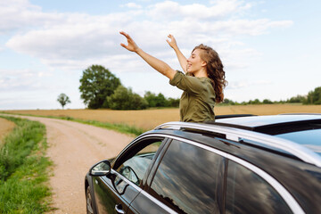 Happy woman on summer road trip travel vacation leaning out car window. Summer trip. Nature,...