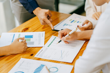 Two people are looking at a graph on a table. One of them is holding a pen. The graph shows a comparison of different data points