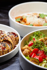 Close up of three bowls with fish ball, leaf vegetable, and plate on table
