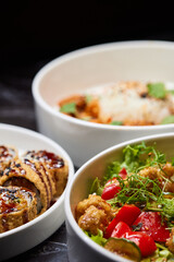 Close up of three bowls with fish ball, leaf vegetable, and plate on table