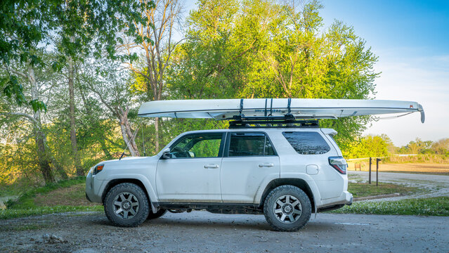 Blackwater, MO, USA - April 22, 2024: Toyota 4Runner SUV with an expedition canoe on roof racks at a shore of the Lamine River in spring scenery.
