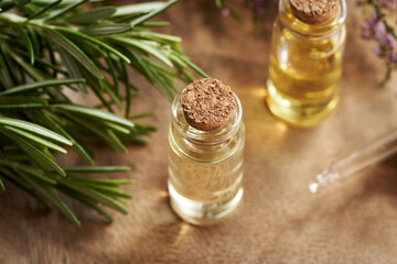 A bottle of aromatherapy essential oil with fresh rosemary twigs