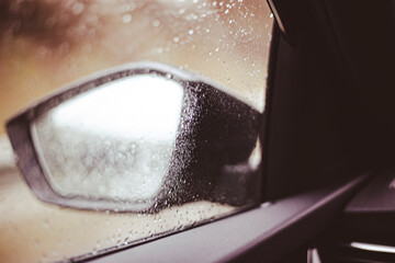 Raindrops falling on the car windscreen with bad visibility on side mirrors car