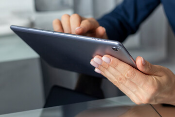 Close up shot of the woman with beautiful hands sitting in the meeting room during business meeting, using tablet. Business