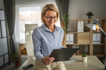Mature woman watch tablet and drink coffee at office at work