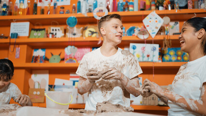 Group of happy diverse children playing clay while wearing muddy shirt at art lesson. Cute...