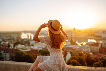 Young girl tourist exploring new city at summer at sunset. Back view. Lifestyle, travel,  nature,...