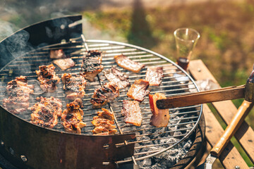 Different types of meat being roasted on barbecue grill outdoors on a sunny day. Barbecue time in...