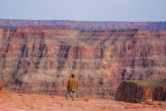 A man enjoys the spectacular view of red mountains at Grand Canyon West. One of the world heritage, a worldwide geological phenomenon known as the Great Unconformity of rock in which 250 million-year-