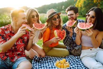 Group of friends having fun eating watermelon on the picnic outdoors. Foods, travel, nature and...