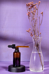 Blank amber glass essential oil bottle with pipette and gypsophila flowers. Skin care concept with natural cosmetics