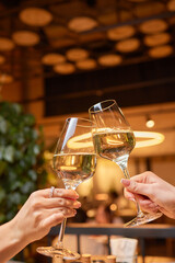 A woman holds a cocktail in her hand, with her fingers wrapped around the glass