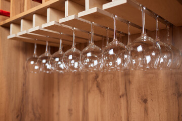 a row of wine glasses hanging from a wooden rack