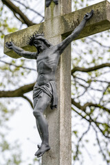 Metal Jesus on a stone cross. - obrazy, fototapety, plakaty
