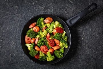 fried juicy sausage and crispy broccoli in skillet