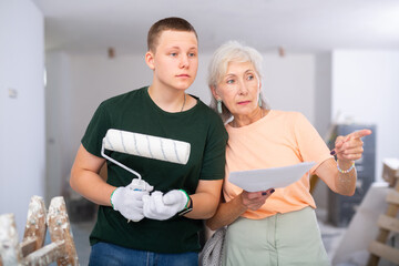 Teenage boy helping senior woman with home improvement works, discussing documentation, planning...