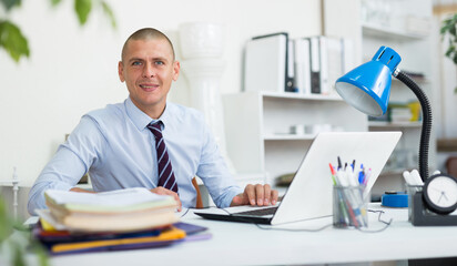 Fototapeta premium Man office manager sitting at table and looking in camera.