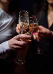 A woman holds a cocktail in her hand, with her fingers wrapped around the glass
