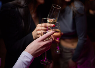 A woman holds a cocktail in her hand, with her fingers wrapped around the glass