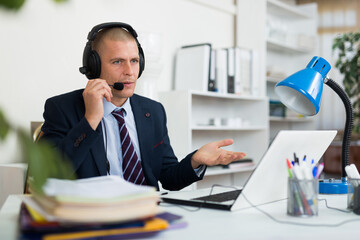 Call center man operator with headset talking with client in agency