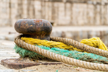 Old mooring bollard with colorful marine ropes