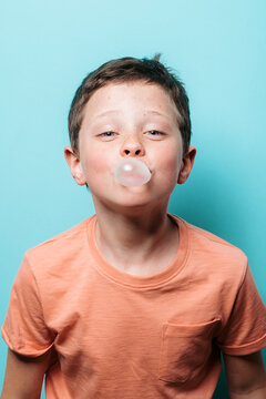 Young boy blowing bubble gum in studio portrait