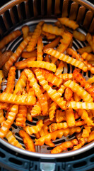 A top down image of an air fryer basket full of crinkle cut French fries