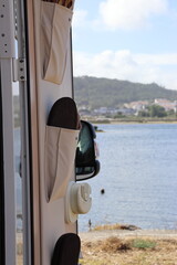Photograph of the view of a lake from the open door of a motorhome. Vertical image.