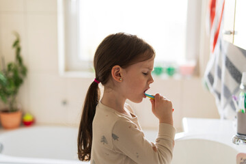 Little girl brushing her teeth in the bathroom. Healthy teeth concept.