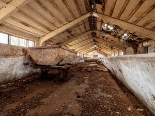 Scene inside old abandoned milk cow farm with feeders, windows and old equipment. Soviet union...