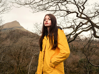 Young teenager girl in yellow jacket on a walk in a dense forest. Travel and tourism concept....