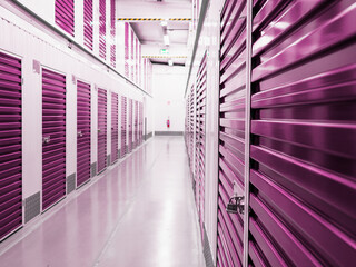 Passage hall with purple color doors in self storage facility. Selective focus. Nobody. Service for private and commercial business use. Clean room environment.