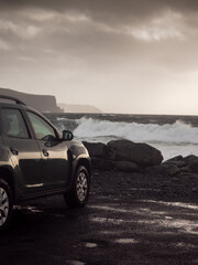 Car parked close to the ocean with view on amazing nature scene with powerful waves. Doolin area, county Clare, Ireland. Travel and tourism concept. Rented car trip theme. Rough Irish landscape