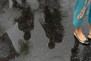 Reflection of Catholic people is seen on the wet ground during Palm Sunday celebration in the city...