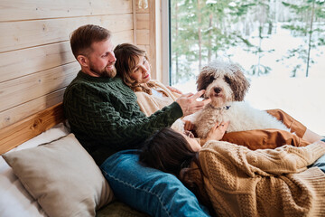 Modern family of three wearing casual clothes spending cold winter day relaxing in bedroom with...