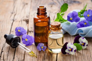 Glass bottle of essential viola oil with fresh violet flowers, beauty treatment, alternative...