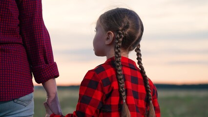 Daughter parent holding hands at sunset. Kid child mom woman mother strolling in field at sunrise....