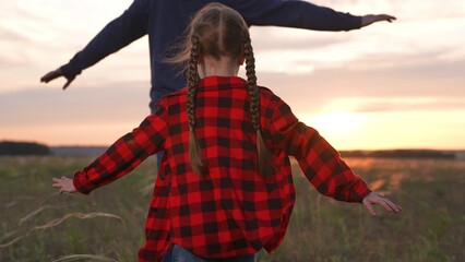 Happy family runs across field, daughter father imagine as airplane pilots dreaming inspired...