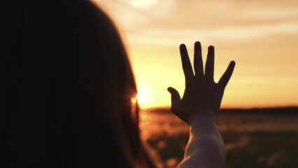 Woman stretched out hand sunset silhouette. Palm arm towards sun catching rays of evening morning...