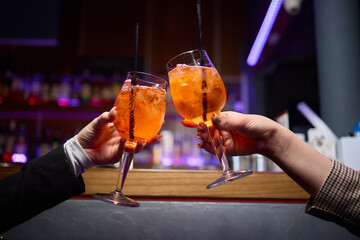 A woman holds a cocktail in her hand, with her fingers wrapped around the glass
