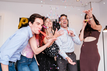 Group of friends at a party in an apartment with confetti and enjoying a celebration together