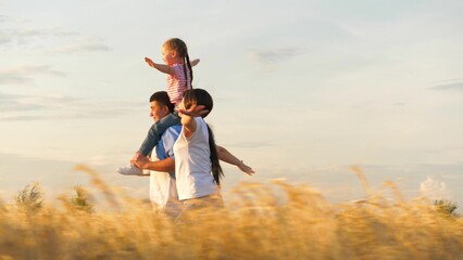 Family running flying plane imagination at sunset dry wheat field side view tracking shot. Happy...