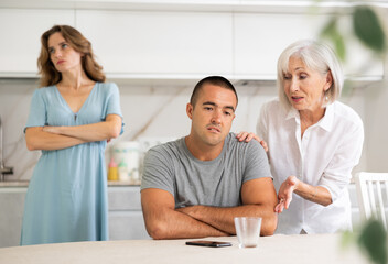 Adult woman during family quarrel with elderly woman and adult man in kitchen