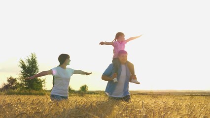 Happy family running flying at sunset dry wheat field together slow motion. Overjoyed father mother...