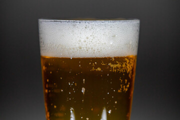 Cold beer dripping foam into glass