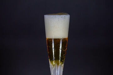 Cold beer dripping foam into glass