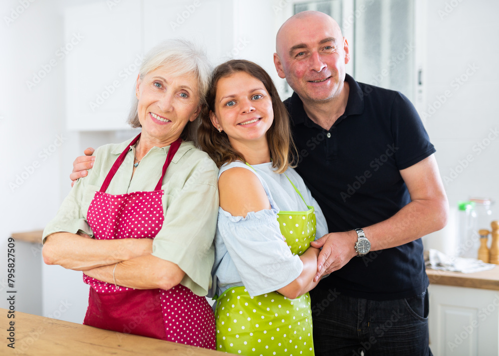 Wall mural Happy husband with young wife and elderly mother in modern kitchen