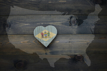 wooden heart with national flag of delaware state near united states of america map on the wooden...