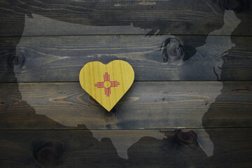 wooden heart with national flag of new mexico state near united states of america map on the wooden...